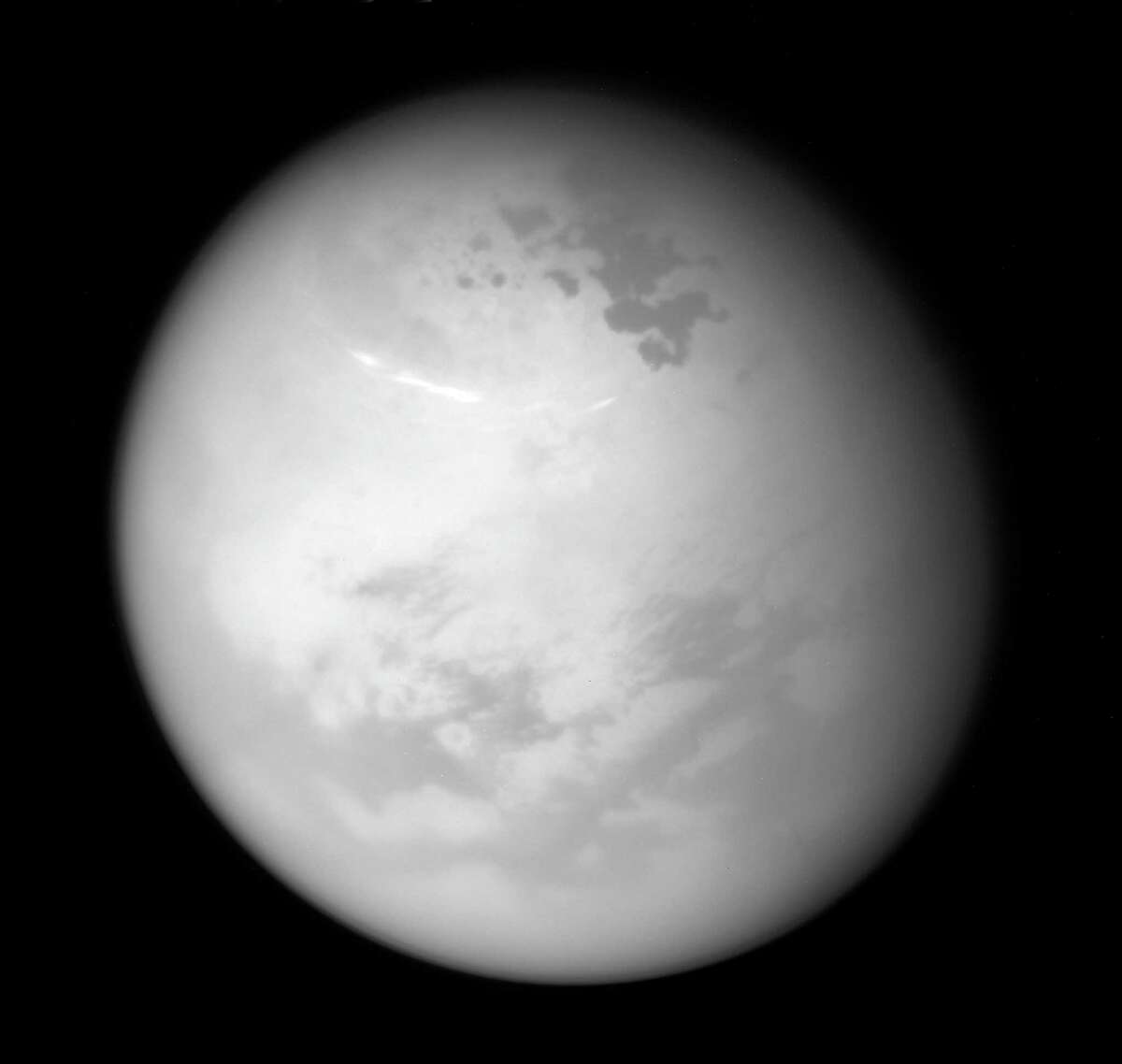 This June 9, 2017 image made available by NASA shows bright methane clouds drifting in the summer skies of Saturn's moon Titan, along with dark hydrocarbon lakes and seas clustered around the north pole, as seen from the Cassini spacecraft. (NASA/JPL-Caltech/Space Science Institute via AP)