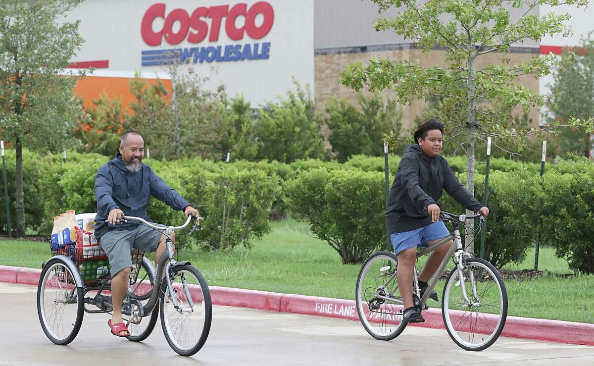 A man and his son pick up supplies on their bicycles from Costco on August 29, 2017, in Pearland, Texas as the city battles with the aftermath of Harvey and resulting floods.