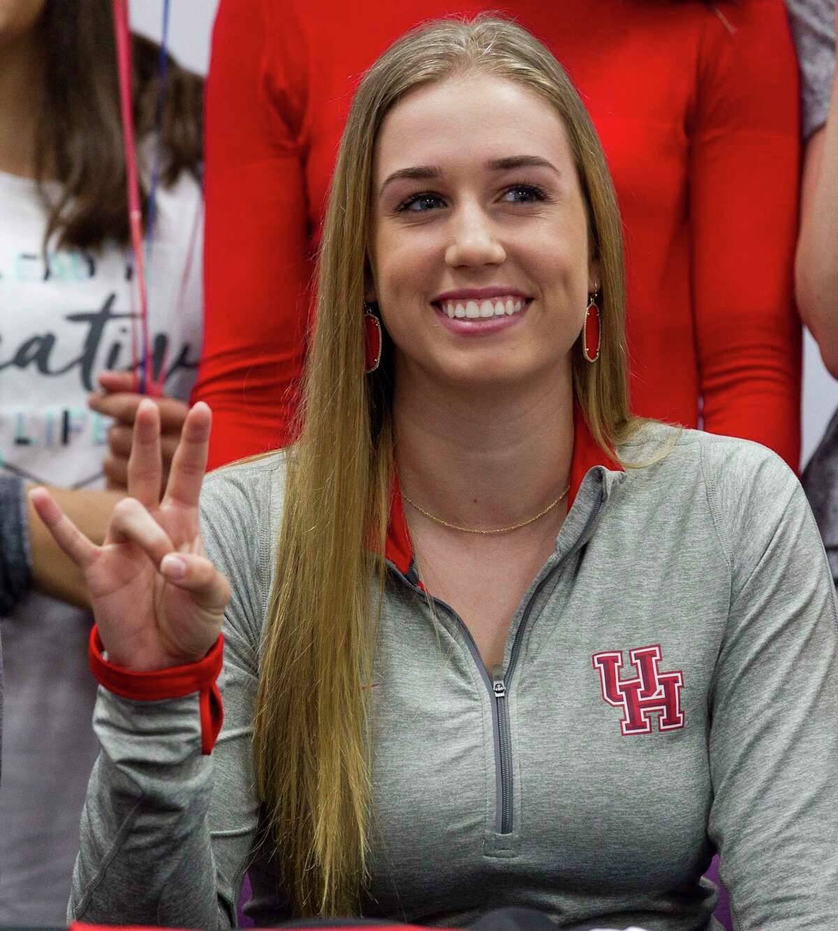 Willis setter Abby Irvine makes the University of Houston hand sign after signing to play volleyball with the Cougars during a signing ceremony at Willis High School Friday, Nov. 11, 2016, in Willis.