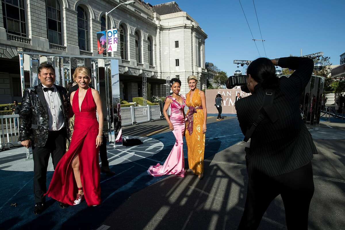 Mark Calvano, Navid Armstrong, Tanya Powell and Karen Caldwell pose for photographs as photographer Vasna Wilson takes a photo (left to right) at the San Francisco Symphony Opening Night Gala at Davies Symphony Hall in San Francisco, Calif., on Thursday, September 14, 2017.