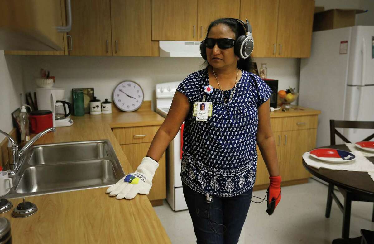 Faculty member Jolly Punchamannil from the School of Nursing at UT Health San Antonio roams in a room attempting to do tasks while outfitted with glasses, gloves and headphones to simulate dementia on Sept. 14, 2017.