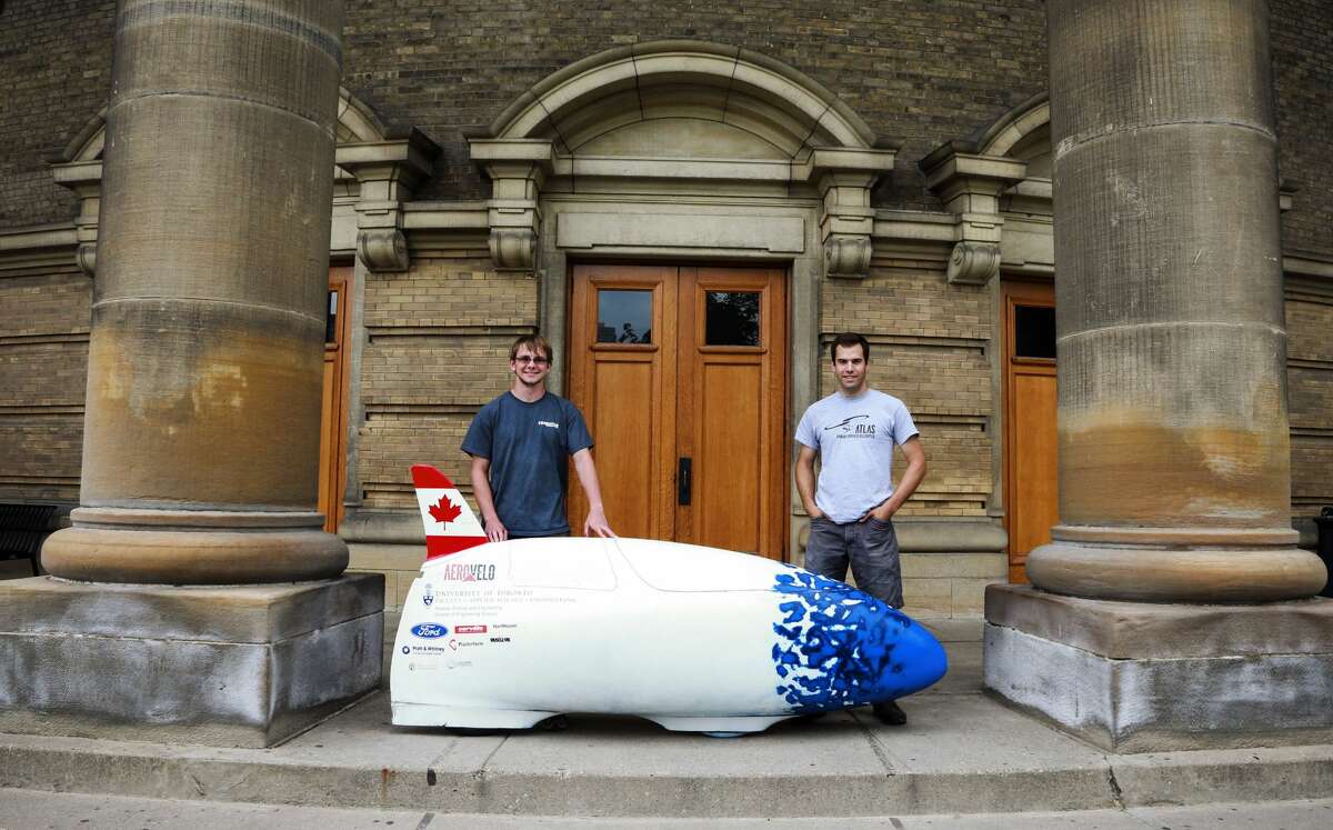 FILE-- Cameron Roberts (R) and Calvin Moes pose by the bike at U of T downtown campus, July 2, 2014. A group of students behind previous projects to build a human-powered ornithopter and helicopter are setting their sights on a new record by building the world's fastest human-powered vehicle. The team's vehicle is expected to hit 140 km/h and will be competing in the World Human-Powered Speed Challenge in Battle Mountain, Nevada this September.