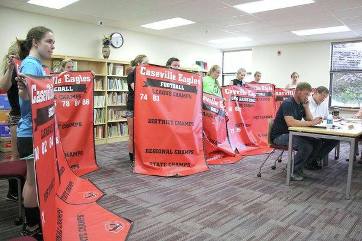 Members of the Caseville varsity volleyball team hold up new banners that were presented to the Caseville Board of Education Wednesday night. The banners, which show the championships for each of the eight varsity sports teams, will soon go up in the new gym. (Chip Burch/Huron Daily Tribune)