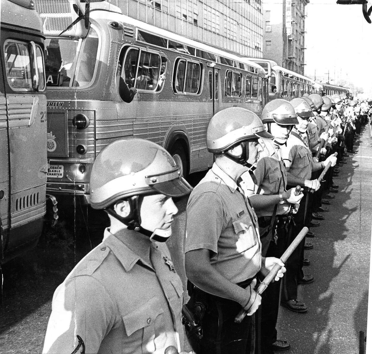Police are escorting buses of inductees through anti-war demonstrators who are blocking access to the Oakland Induction Center, October 16, 1967 Draft and Vietnam War protesters Phot ran 10/17/1967, p. 1