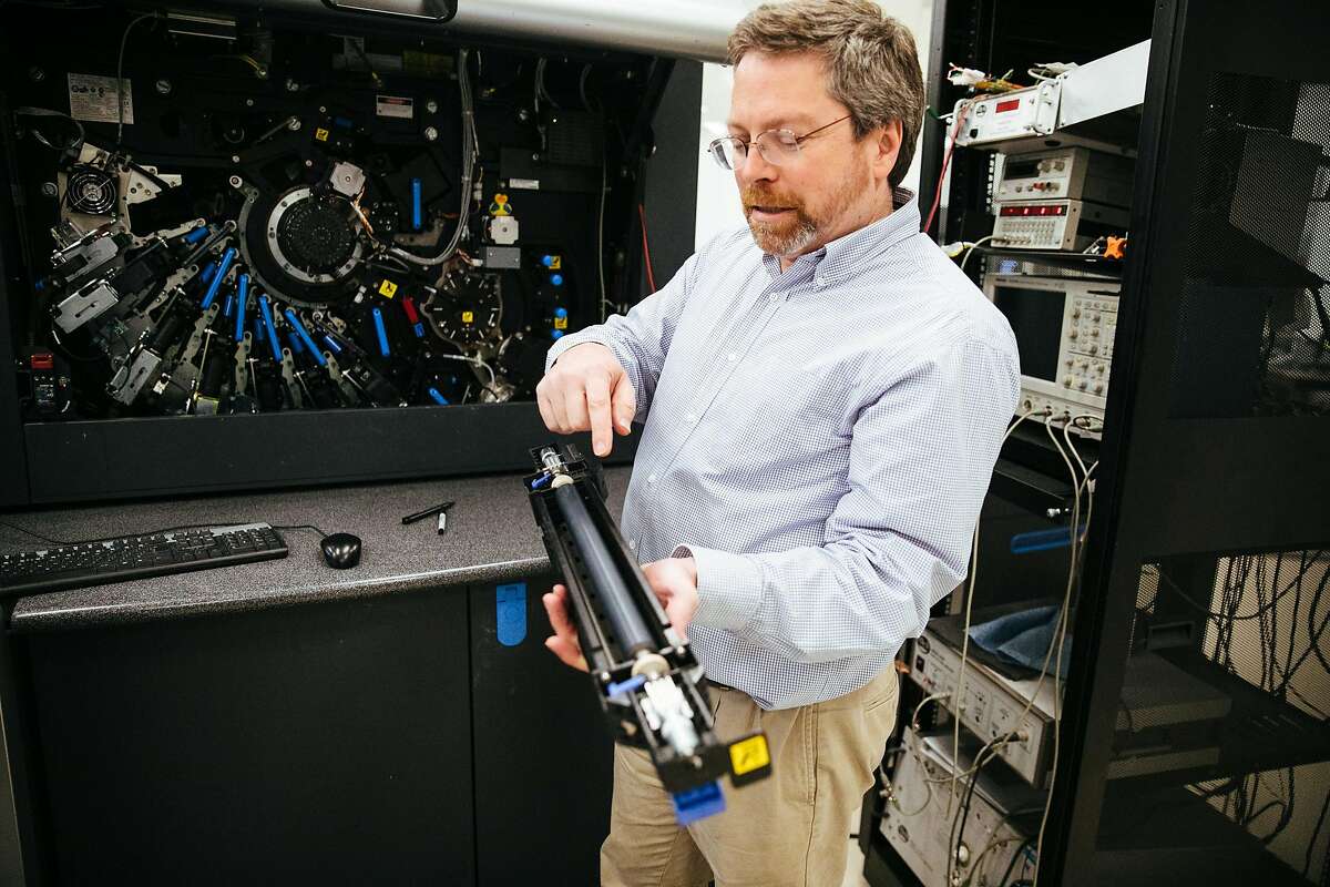 副主任Keith Moore手持惠普Indigo 7500数码印刷机的充电滚筒。