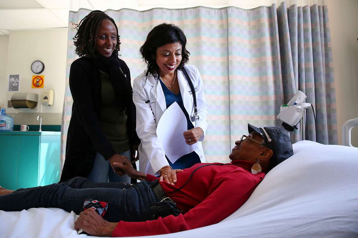 From left: Nurse care coordinator Eva Mureithi and medical director and golden compass Golden Compass program coordinator Monica Gandhi check up on Hulda Brown at San Francisco General Hospital's Ward 86 on Friday, Sept. 15, 2017, in San Francisco, Calif. Brown, age 73, was diagnosed HIV positive in 1991. She's been getting treatment at the hospital for more than two decades.