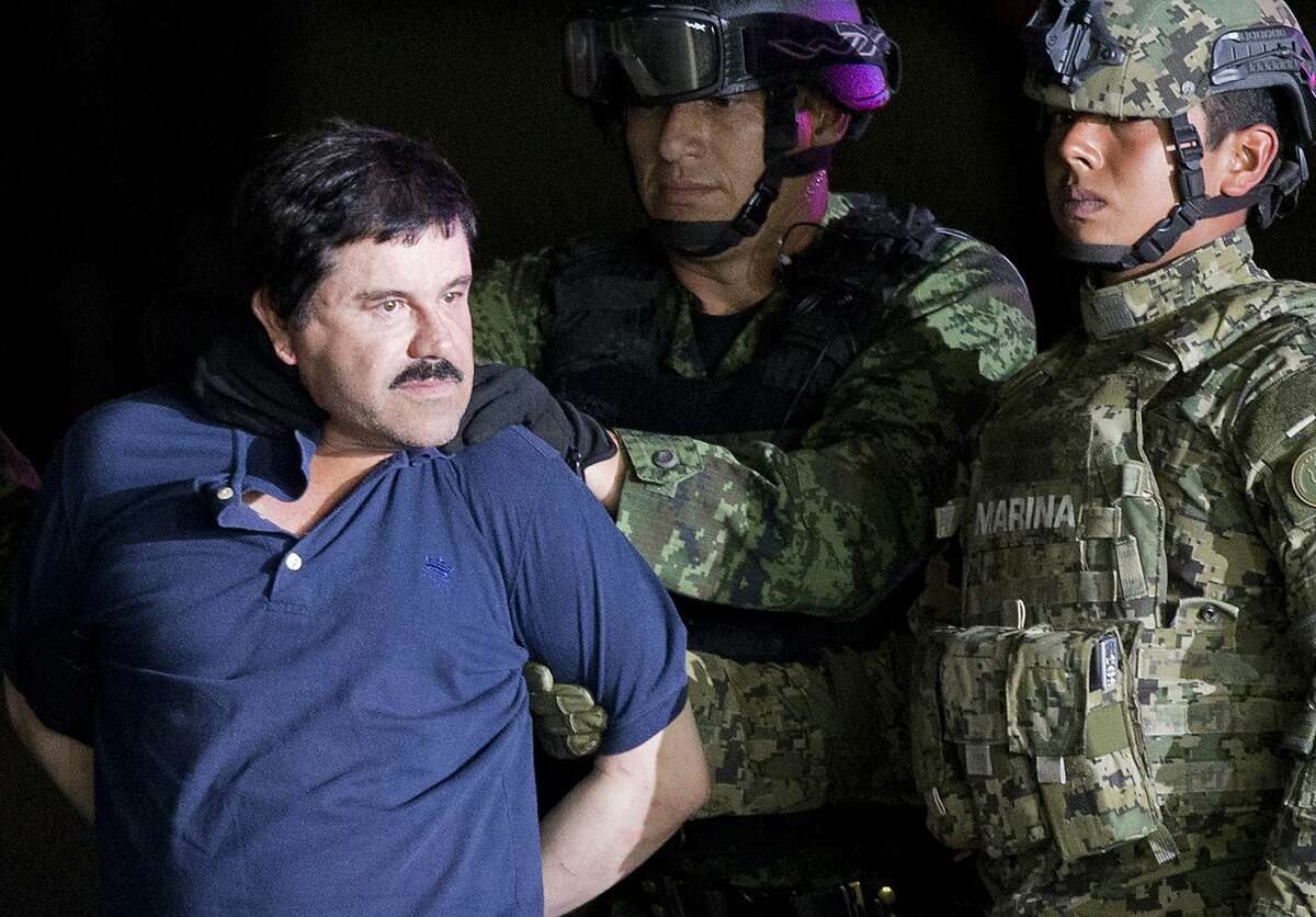 FILE - In this Jan. 8, 2016 file photo, a handcuffed Joaquin "El Chapo" Guzman is made to face the press as he is escorted to a helicopter by Mexican soldiers and marines at a federal hangar in Mexico City. A federal judge says he won’t dismiss the New York drug trafficking case against Mexican drug lord Joaquin "El Chapo" Guzman. Judge Brian Cogan ruled Friday, Sept. 15, 2017 that El Chapo can’t raise the issue without protest or objection from Mexico. (AP Photo/Eduardo Verdugo, File)