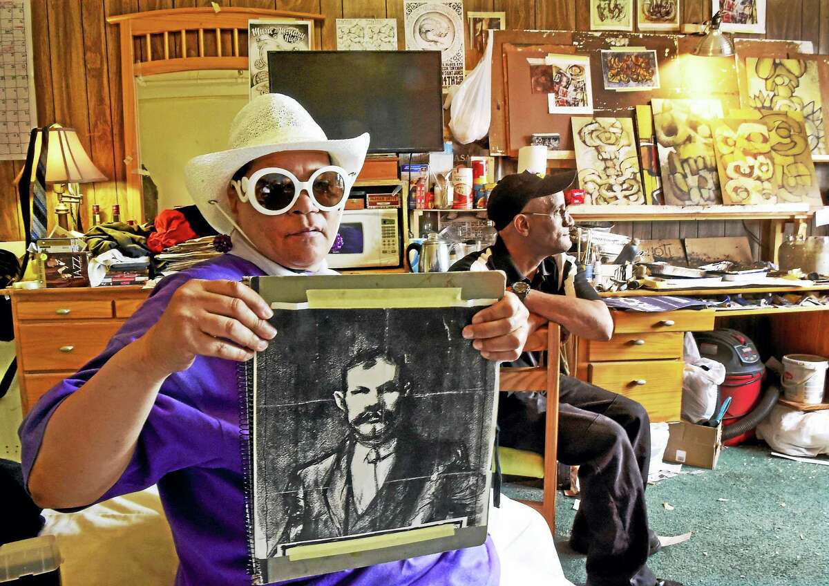 Elaine Sands, 66, left, holds a portrait of the great-grandfather of artist/illustrator Kevin Sanchez Walsh, with Stacey Lewis, 52, in a room of at the Duncan Hotel on Chapel Street in New Haven that is the home and studio of Mr. Walsh. Sands and Lewis, along with Walsh, are long-term residents of the affordable Duncan Hotel who must leave because it is will be developed as an upscale boutique hotel.