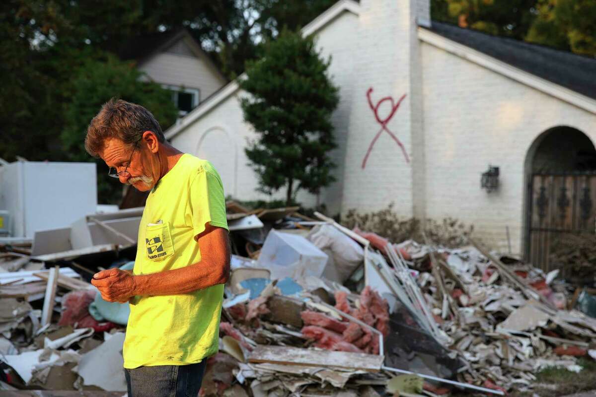 Contractor Ricky Green of Alabama finishes a day of picking up large debris in a Memorial-area neighborhood. A red X signifying that someone died inside still marks Robert Arthur Haines' house on Langwood.