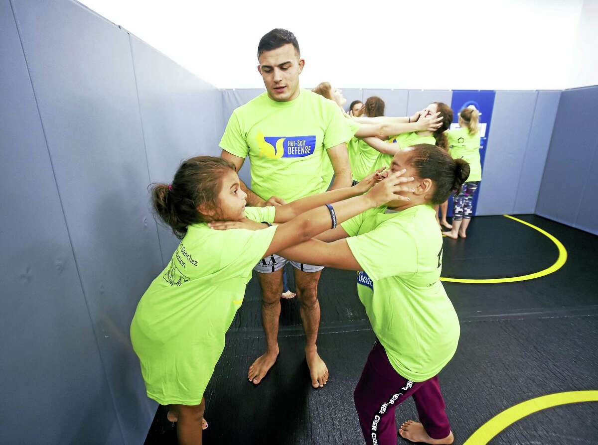 Arnold Gold / Hearst Connecticut Media Instructor and Fighting Arts Academy owner Nick Newell, center, observes Kamille Perez, left, 8, and Naralis Velazquez, 9, of Bridgeport practice how to counter an attacker during the self-defense class.