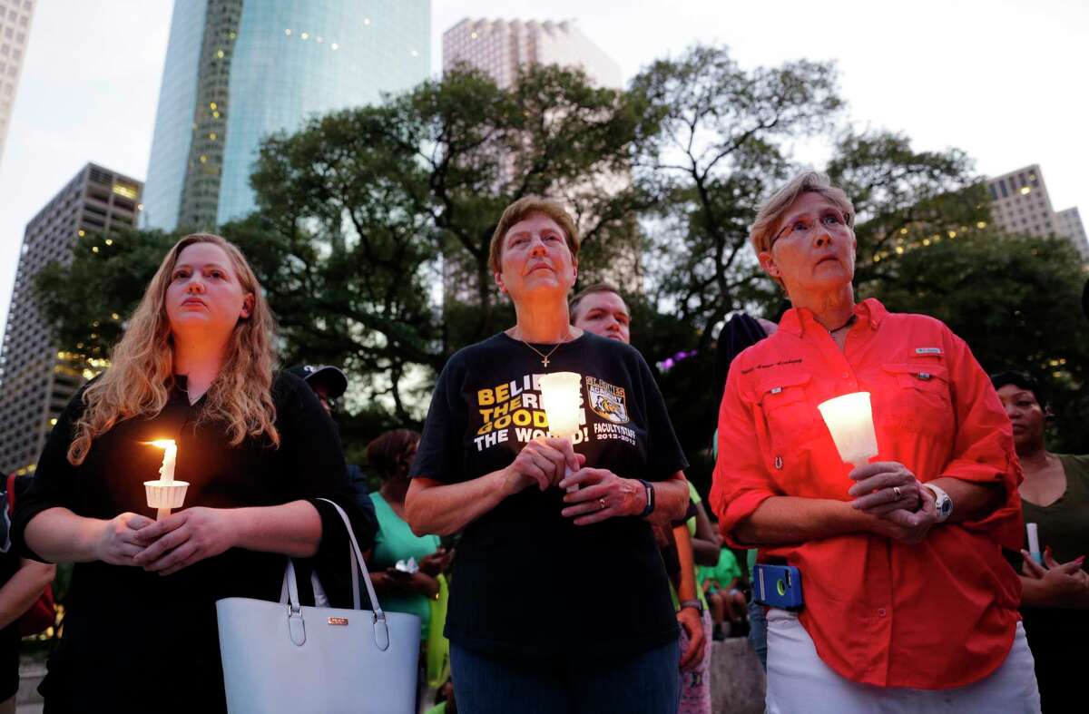 Kimberly Burris, Jane Meyer and Mary Brenda hold candles during a candlelight ceremony in honor of the victims of Hurricane Harvey, held on the steps of City Hall in Houston Sunday. Several dozen residents participated during the hour-long service.