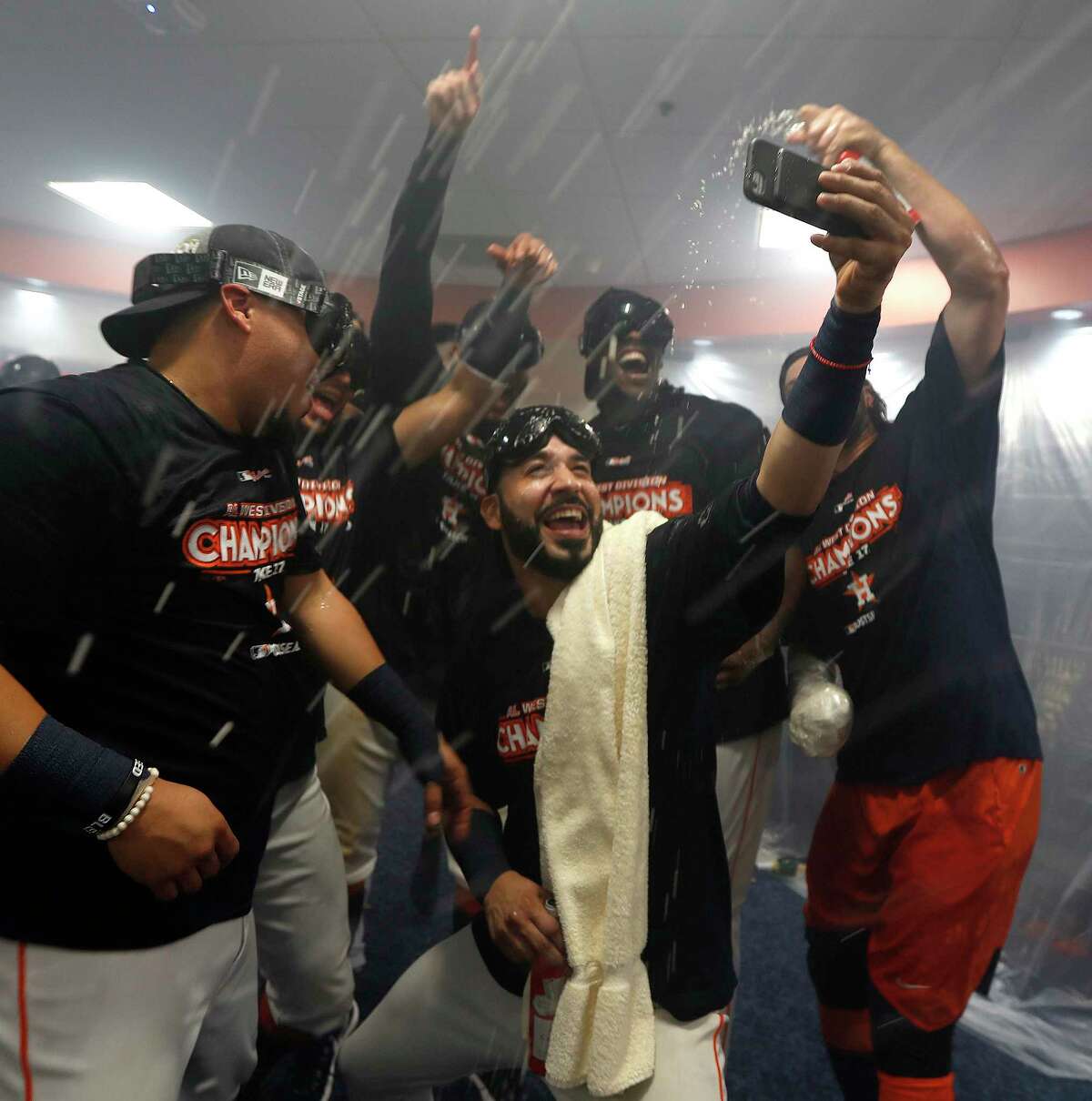Marwin Gonzalez, center, takes a selfie with teammates amid streams of beer and Champagne on Sunday as the Astros celebrate clinching the AL West title.
