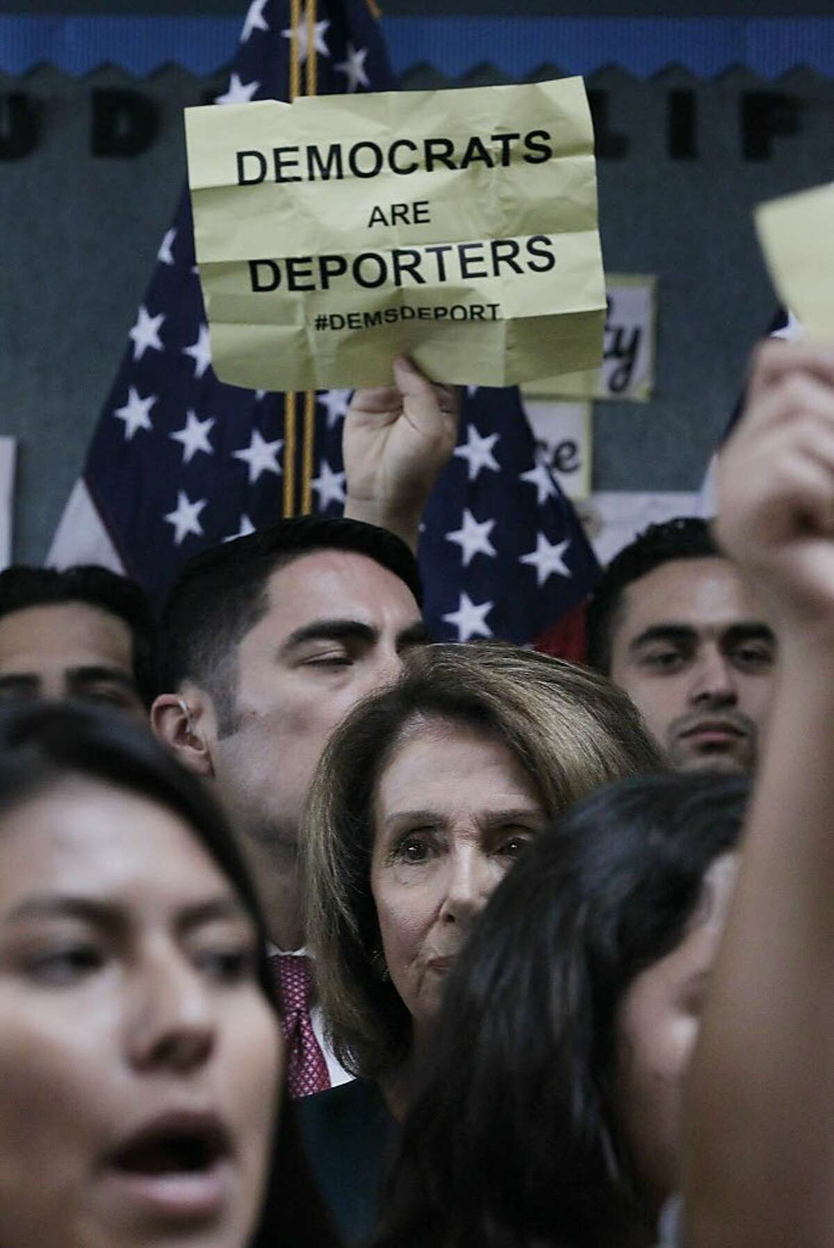 U.S. House Minority Leader Nancy Pelosi (center) watches as protesters demonstrate during a press conference on the DREAM ACT on Monday, September 18, 2017 in San Francisco, Calif.