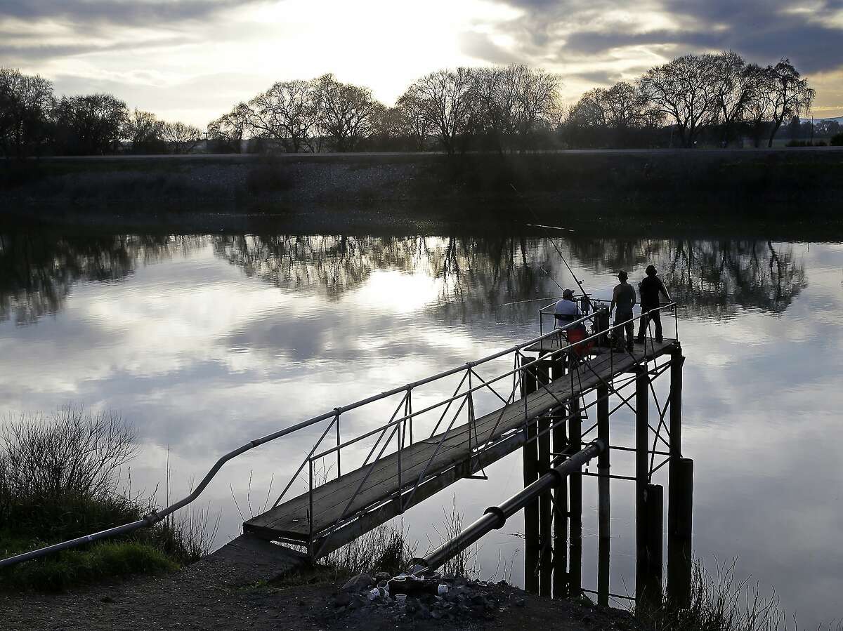 FILE- In this Feb. 23, 2016 file photo, people try to catch fish along the Sacramento River in the San Joaquin-Sacramento River Delta, near Courtland, Calif. California has released a key environmental report supporting Gov. Jerry Brown's plans for two giant north-south water tunnels. Brown's administration environmental-impact report Thursday, Dec. 22, 2016, for the project clears another regulatory hurdle for the proposed tunnels. (AP Photo/Rich Pedroncelli, File)