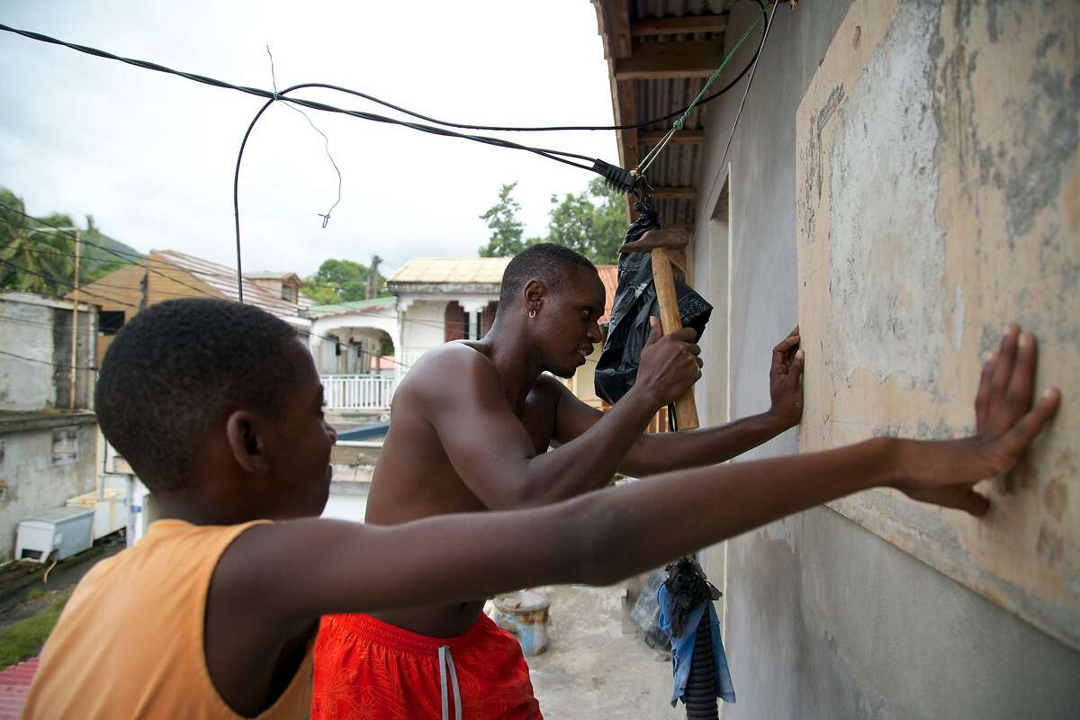 A man and a boy nail a board over a window on September 18, 2017, in Basse-Terre, on the Fench Caribbean island of Guadeloupe, as Hurricane Maria approaches the Caribbean. Hurricane Maria strengthened rapidly on September 18 as it blasted towards the eastern Caribbean, forcing exhausted islanders -- still recovering from megastorm Irma -- to brace for the worst again. The US National Hurricane Center (NHC) said the "major hurricane" had intensified to Category 3 as it approached the French island of Guadeloupe, the base for relief operations for several islands devastated by Irma this month. / AFP PHOTO / Cedrick Isham CALVADOSCEDRICK ISHAM CALVADOS/AFP/Getty Images