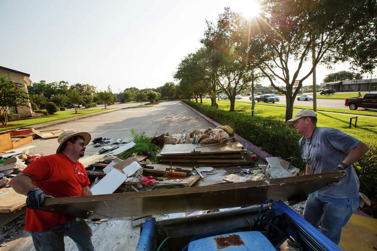 Colbin Holtz, left, and Steven Hanks, right, throw out damaged furniture, doorways and items as volunteers clean up First United Methodist Church in Dickinson earlier this month to prepare for Sunday services. Hauling away the debris could take months, city officials say.