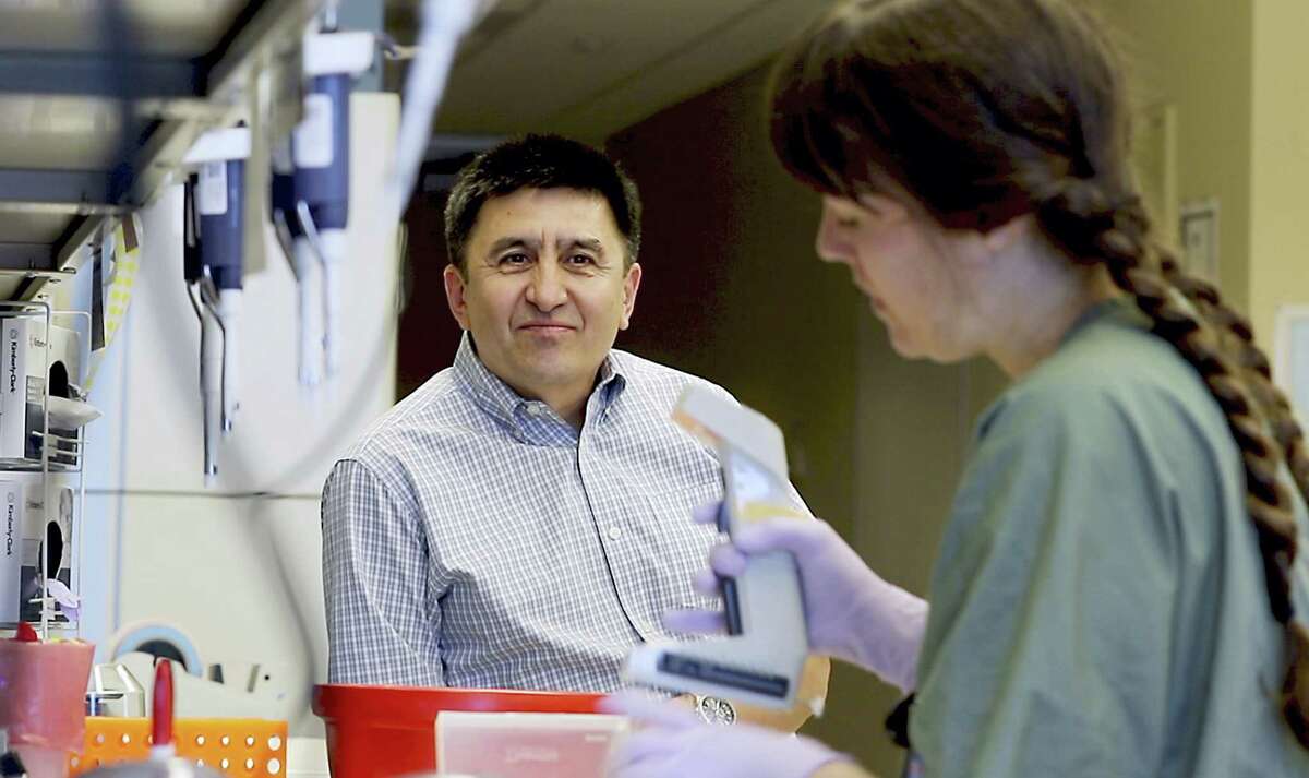 In this July 31, 2017, photo provided by Oregon Health & Science University, Shoukhrat Mitalipov, left, talks with research assistant Hayley Darby in the Mitalipov Lab at OHSU in Portland, Ore. Mitalipov led a research team that, for the first time, used gene editing to repair a disease-causing mutation in human embryos, laboratory experiments that might one day help prevent inherited diseases from being passed to future generations.