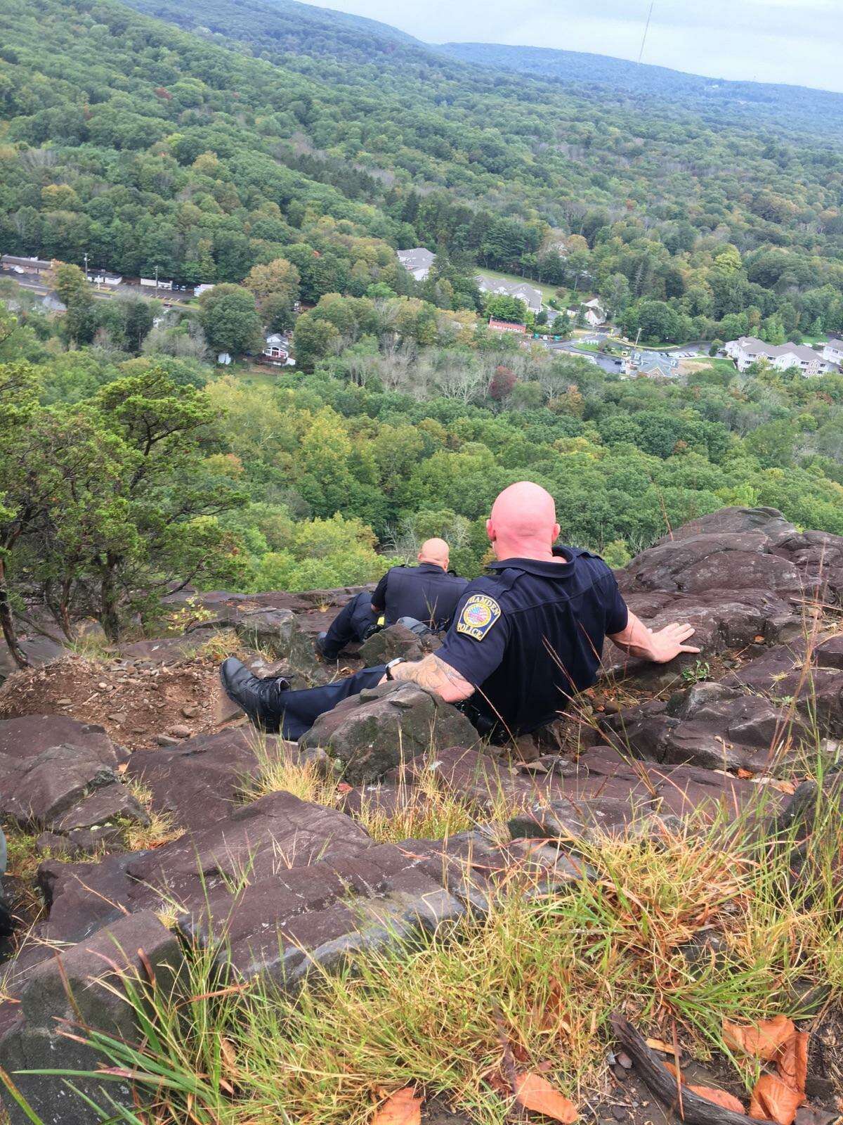 Hamden Police officers Paul Calamita and Timothy Mckeon on Sleeping Giant mountain talking to a distraught woman sitting at the edge of the cliff.