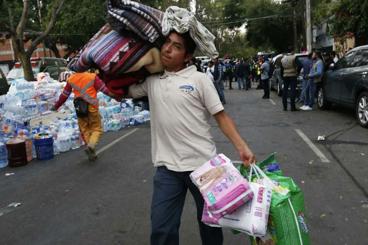 A volunteer carries blankets and diapers Wednesday to a site affected by the earthquake in Mexico City. The Mexican Consulate in San Antonio has asked for monetary donations to the Mexican Red Cross rather than in-kind donations.
