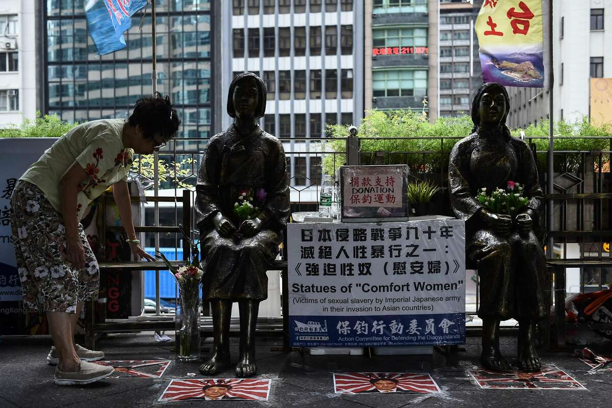 A woman places flowers next to two "comfort women" statues ahead of a protest to mark the 86th anniversary of the 'Mukden Incident' in Hong Kong on September 18, 2017. The 'Mukden Incident' took place in 1931, when Japanese soldiers blew up a railway in Manchuria as a pretext to take control of the entire northeastern region a few years before the outbreak of World War II. / AFP PHOTO / Anthony WALLACEANTHONY WALLACE/AFP/Getty Images