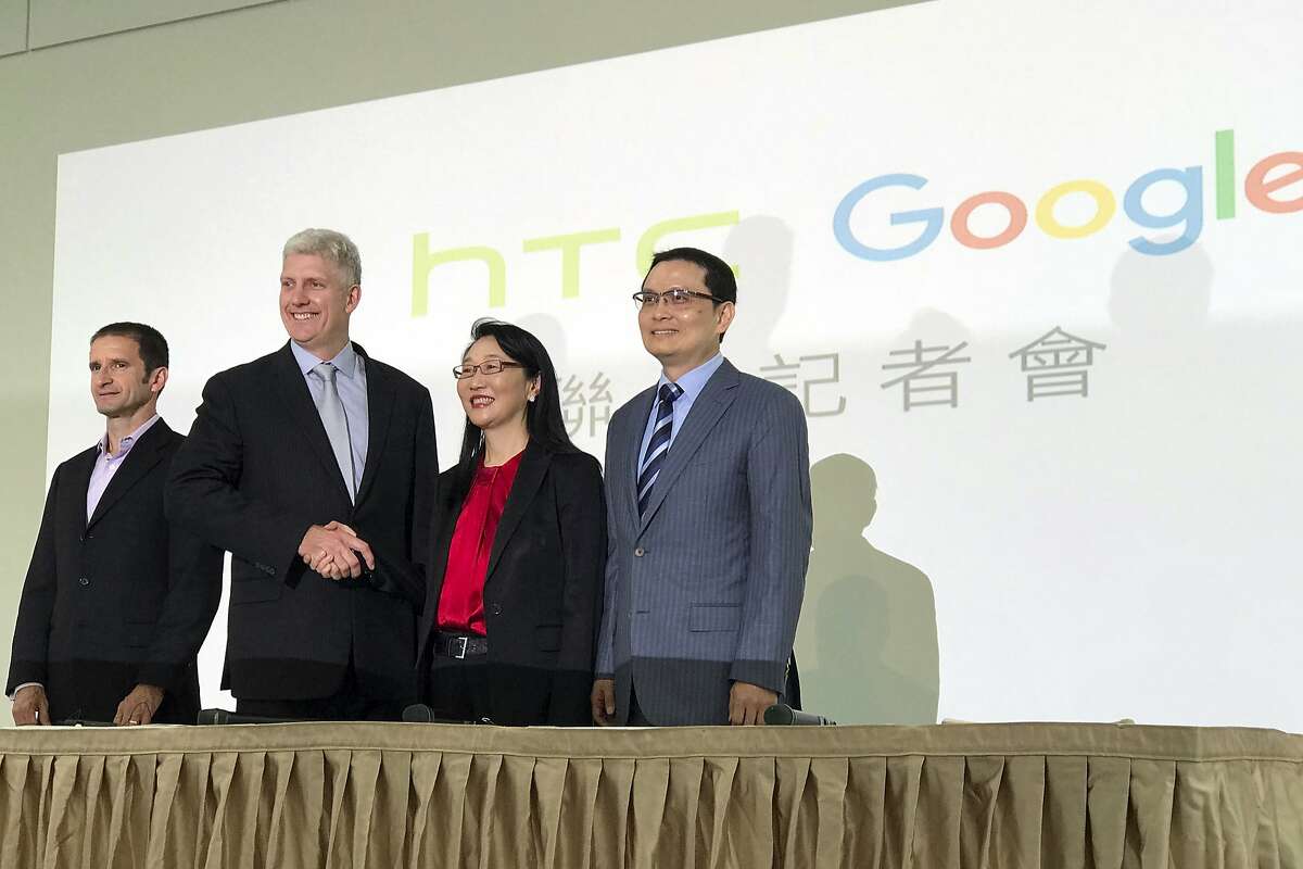 Rick Osterloh, senior vice president of hardware for Google, second from left, and Cher Wang, chairperson of HTC, shake hands during a press conference in New Taipei City, Taiwan, Thursday, Sept. 21, 2017. Google is biting off a big piece of device manufacturer HTC for $1.1 billion to expand its efforts to build phones, speakers and other gadgets equipped with its arsenal of digital services. At left is Mario Queiroz, vice president of product management at Google, and at right is Chia-Lin Chang, president of smartphones and connected devices for HTC. (AP Photo/Johnson Lai)