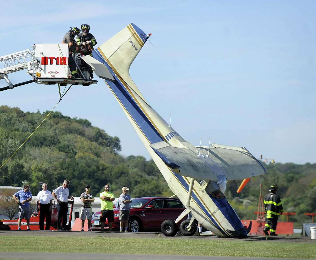 The Danbury Fire Department hooks up the tail of a plane in order to lower it Friday after the pilot experienced a rough landing at Danbury Airport, Friday, Sept. 22, 2017.