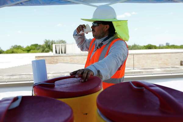 Guillermo Munoz takes a drink of water as Beldon Roofing workers take on a job at Sunshine Cottage during the heat of the day on Friday, July 21, 2017.