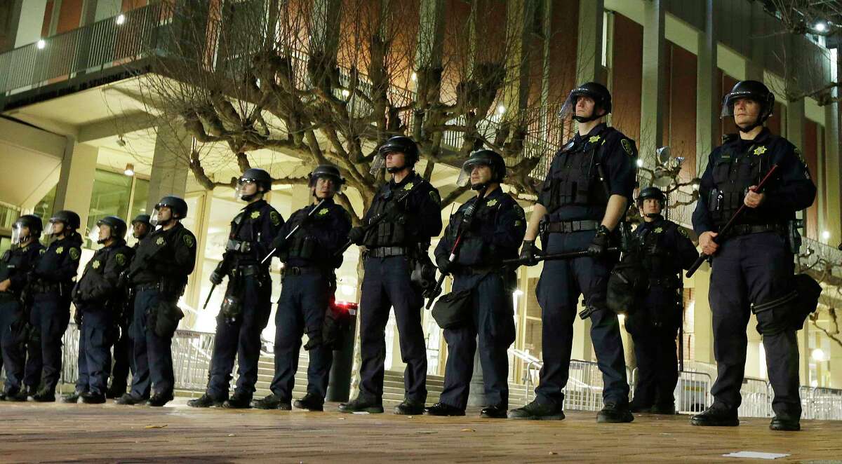 FILE - In this Feb. 1, 2017 file photo, University of California, Berkeley police guard the building where Breitbart News editor Milo Yiannopoulos was to speak. Right-wing showman Milo Yiannopoulos wanted to hold a "Free Speech Week" at the University of California, Berkeley with a planned lineup including conservative firebrands Steve Bannon and Ann Coulter. 