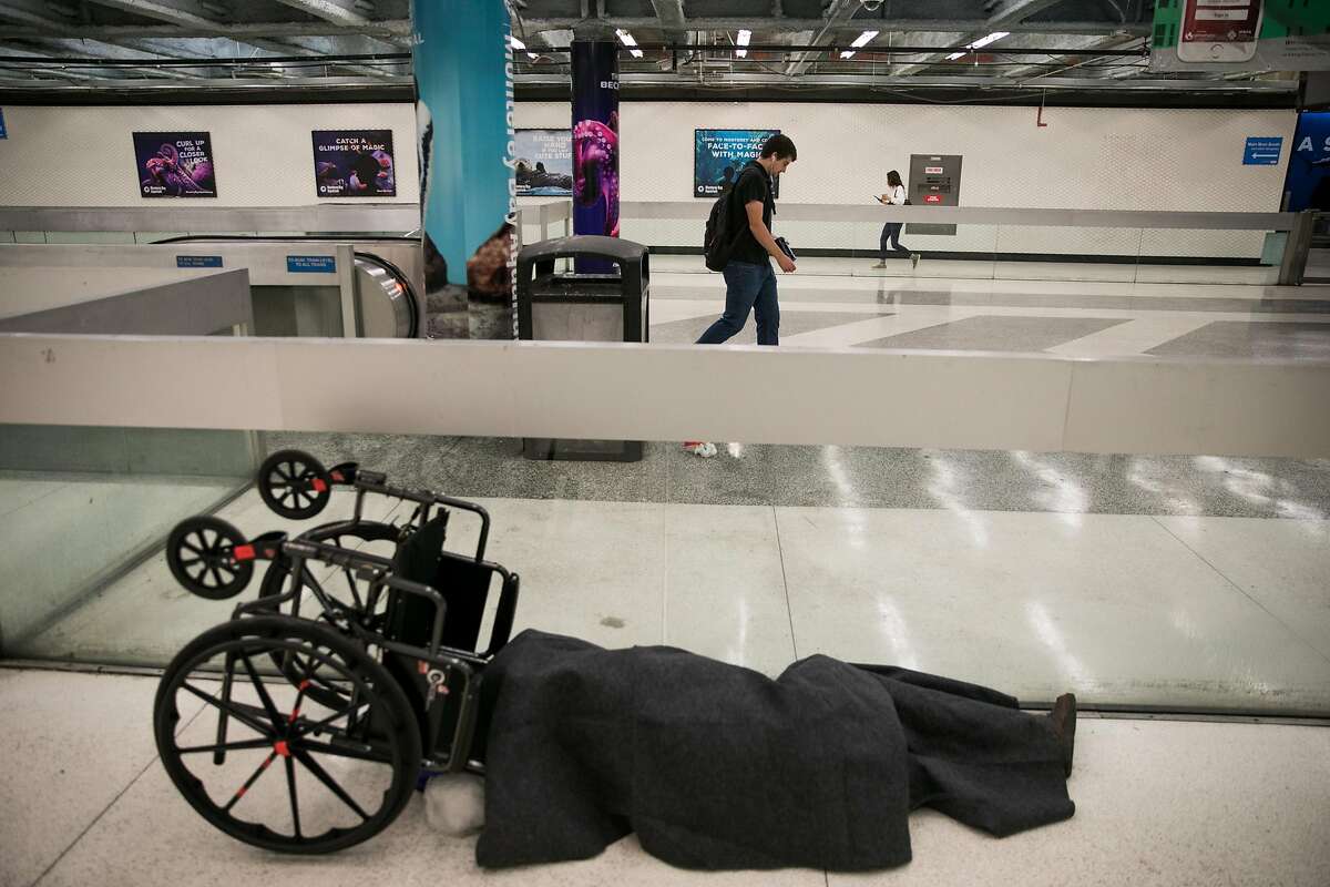 A homeless man is seen as BART commuters make their way through the Powell Street BART station in San Francisco, Calif. Thursday, July 13, 2017.