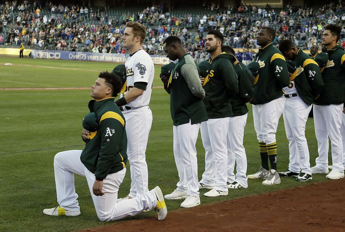 Oakland Athletics catcher Bruce Maxwell kneels during the National Anthem before the start of a baseball game against the Texas Rangers Saturday, Sept. 23, 2017, in Oakland, Calif. Bruce Maxwell of the Oakland Athletics has become the first major league baseball player to kneel during the national anthem. (AP Photo/Eric Risberg)