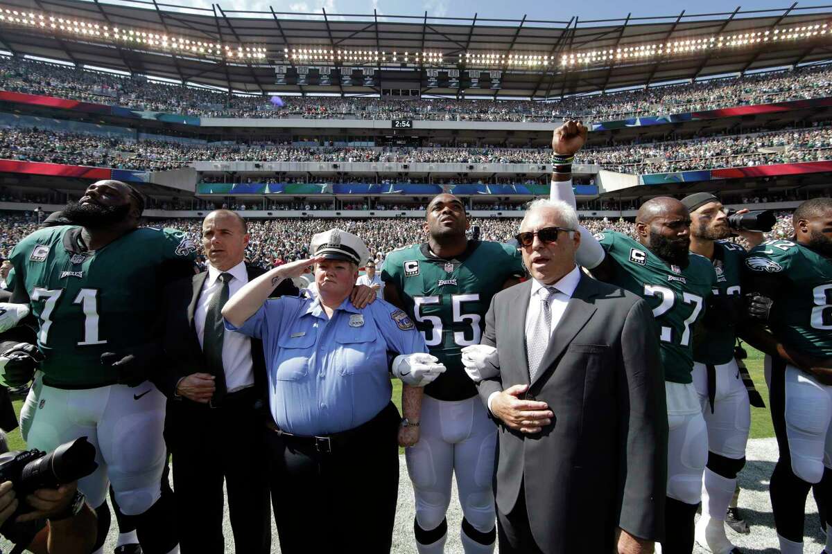 Philadelphia Eagles players and owners Jeffrey Lurie stand for the national anthem before an NFL football game against the New York Giants, Sunday, Sept. 24, 2017, in Philadelphia. Eagles' Malcolm Jenkins raises his fist next to Lurie.