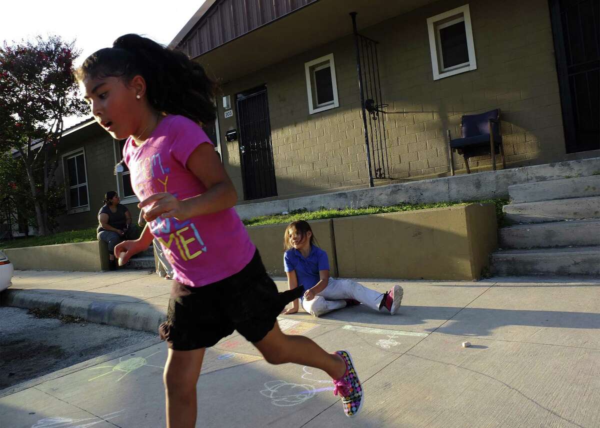 Aeris McLeland (foreground), 6, runs to pick up more chalk as her friend, Emilie Peña, 7, draws a picture of a house on the sidewalk in front of McLeland’s apartment in Alazan Courts. The San Antonio Housing Authority will seek another federal Choice Neighborhoods grant with plans to potentially tear down and redevelop the property, which is the city’s oldest public housing complex.