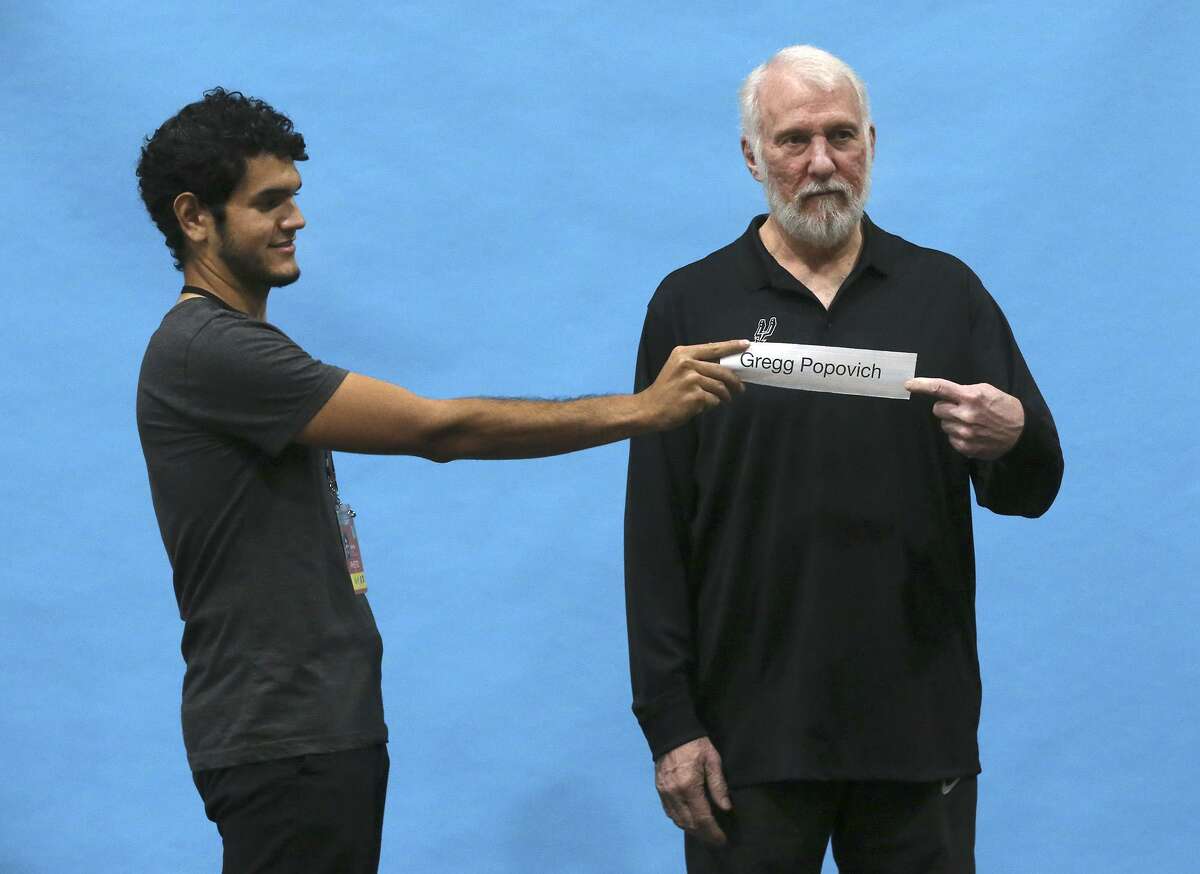 San Antonio Spurs coach Gregg Popovich gets ready for his portrait after a press conference during Spurs media day Monday September 25, 2017. Holding the name plate (left) is David Guel.