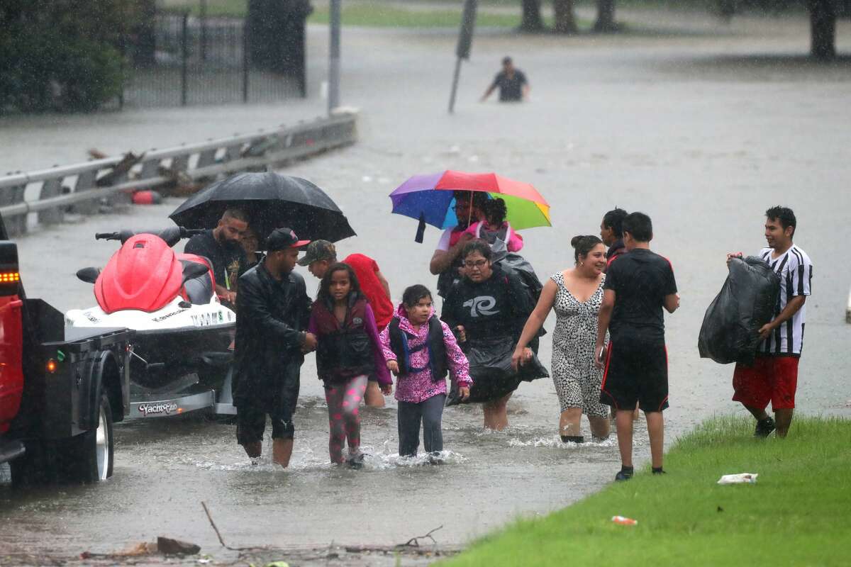 Families walk away from the flooded apartment complex Bayou Parc at Oak Forest by the White Oak Bayou, Sunday, Aug. 27, 2017, in Houston. ( Marie D. De Jesus / Houston Chronicle )