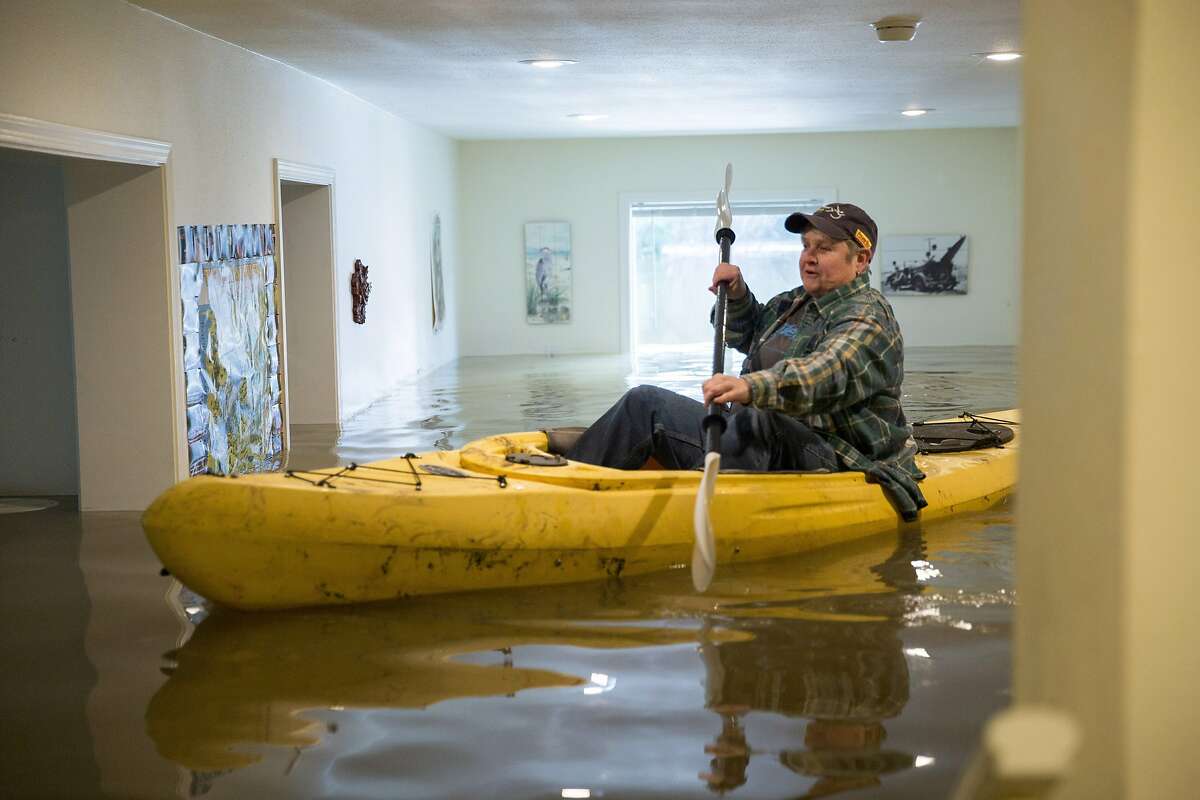 Lorin Doeleman uses a kayak to check her flooded home on Wednesday, Jan. 11, 2017 in Guerneville, Calif. She is moving her belongings to her Sacramento home.