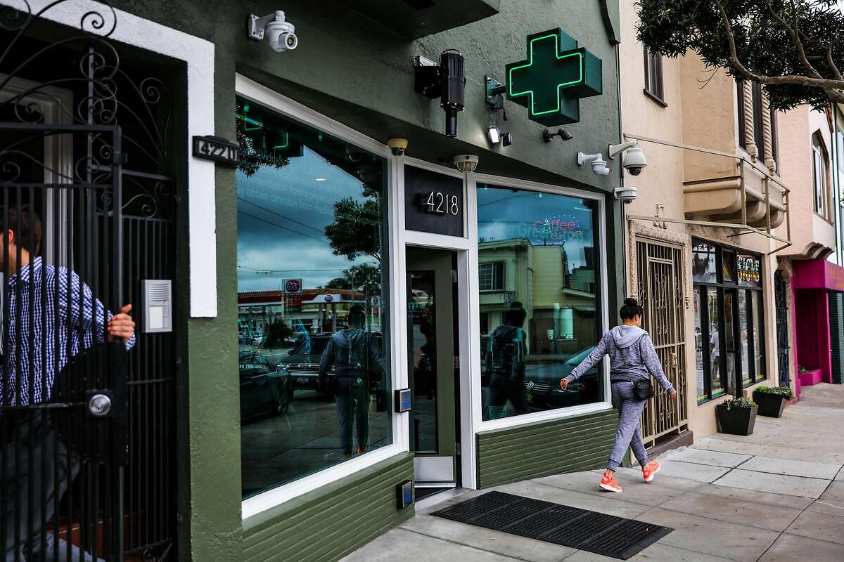 People walk by the exterior of cannabis dispensary, The Green Cross, in San Francisco, California, on Friday, Oct. 28, 2016.