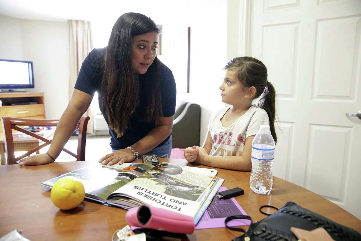 Lori Bailey helps her youngest, Shiloh Bailey, with homework as she manages her children, just home from school, at an apartment in Northwest in San Antonio on September 19, 2017.