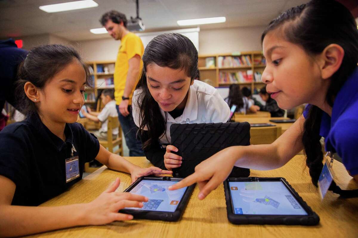 Fourth graders Ciclady Martinez, 9, (from left) Paulina Perales, 9, and Yasmin Lepe, 9, play on an App called "Lightbot Hour," that teaches introductory coding concepts Monday Dec. 7, 2015 during an Hour of Code at Walzem Elementary School. In honor of Computer Science Education Week, students around the world will participate this week in the Hour of Code.