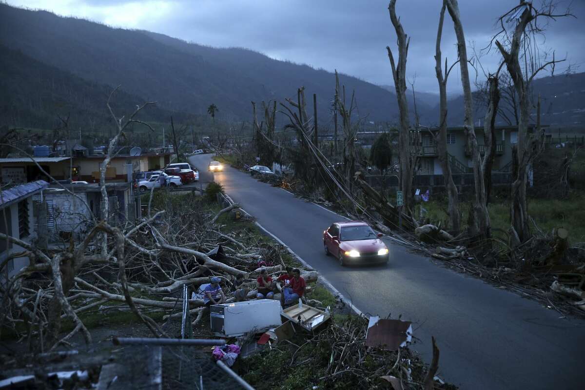 Neighbors sit on a couch outside their destroyed homes as sun sets in the aftermath of Hurricane Maria, in Yabucoa, Puerto Rico, Tuesday, Sept. 26, 2017. Governor Ricardo Rossello and Resident Commissioner Jennifer Gonzalez, the islandâs representative in Congress, have said they intend to seek more than a billion in federal assistance and they have praised the response to the disaster by President Donald Trump, who plans to visit Puerto Rico next week, as well as FEMA Administrator Brock Long. (AP Photo/Gerald Herbert)