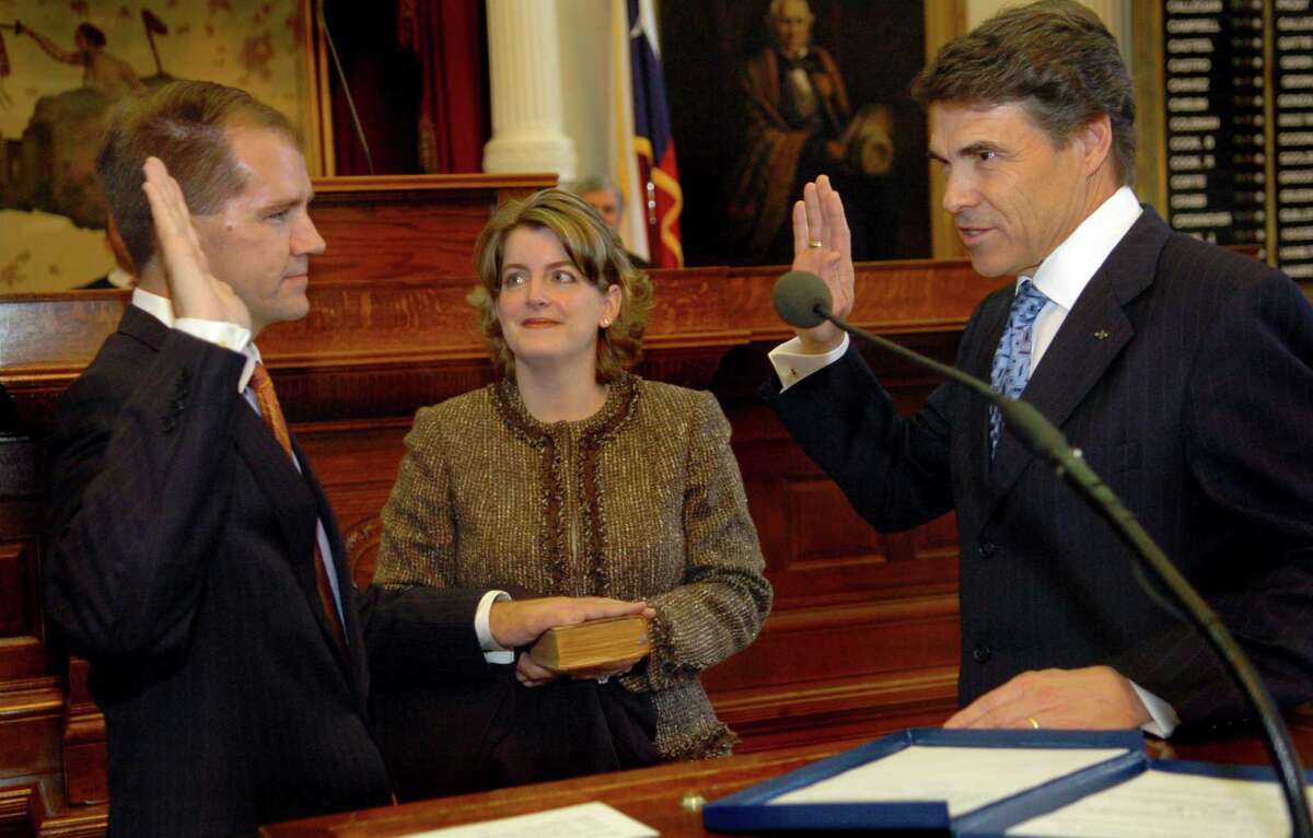 Don Willett, left, is sworn in to the state Supreme Court by Gov. Rick Perry, right, as Tiffany Willett, center, Don Willett's wife, holds the Bible at the State Capitol in Austin, Texas, on Monday, Nov. 21, 2005. (AP Photo/Austin American-Statesman, Rodolfo Gonzalez)
