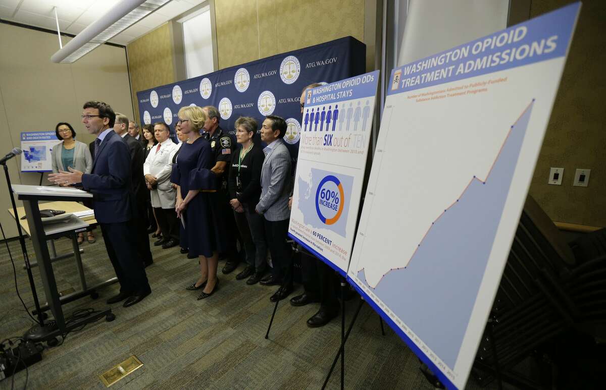 Washington Attorney General Bob Ferguson, second from left, talks to reporters Thursday, Sept. 28, 2017, in Seattle, as he stands near a chart detailing the increase of admissions for opioid addiction treatment in Washington state. Ferguson said Thursday that the state and the city of Seattle are filing lawsuits against several makers of opioids, including Purdue Pharma, seeking to recoup costs incurred by government when the drugs, which many officials blame for a national addiction crisis, are abused. (AP Photo/Ted S. Warren)