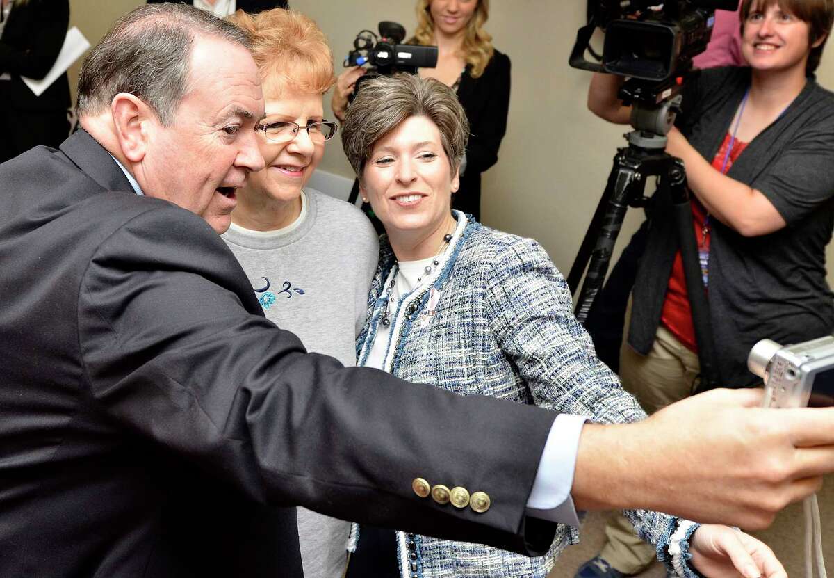 Mike Huckabee, former Arkansas governor and 2008 presidential candidate, left, takes a selfie with Jackie Magee, of Sioux City, Iowa, center, and Republican U.S. Senate candidate Joni Ernst, at Woodbury County Republican election headquarters in Sioux City. (AP Photo/The Sioux City Journal, Tim Hynds)