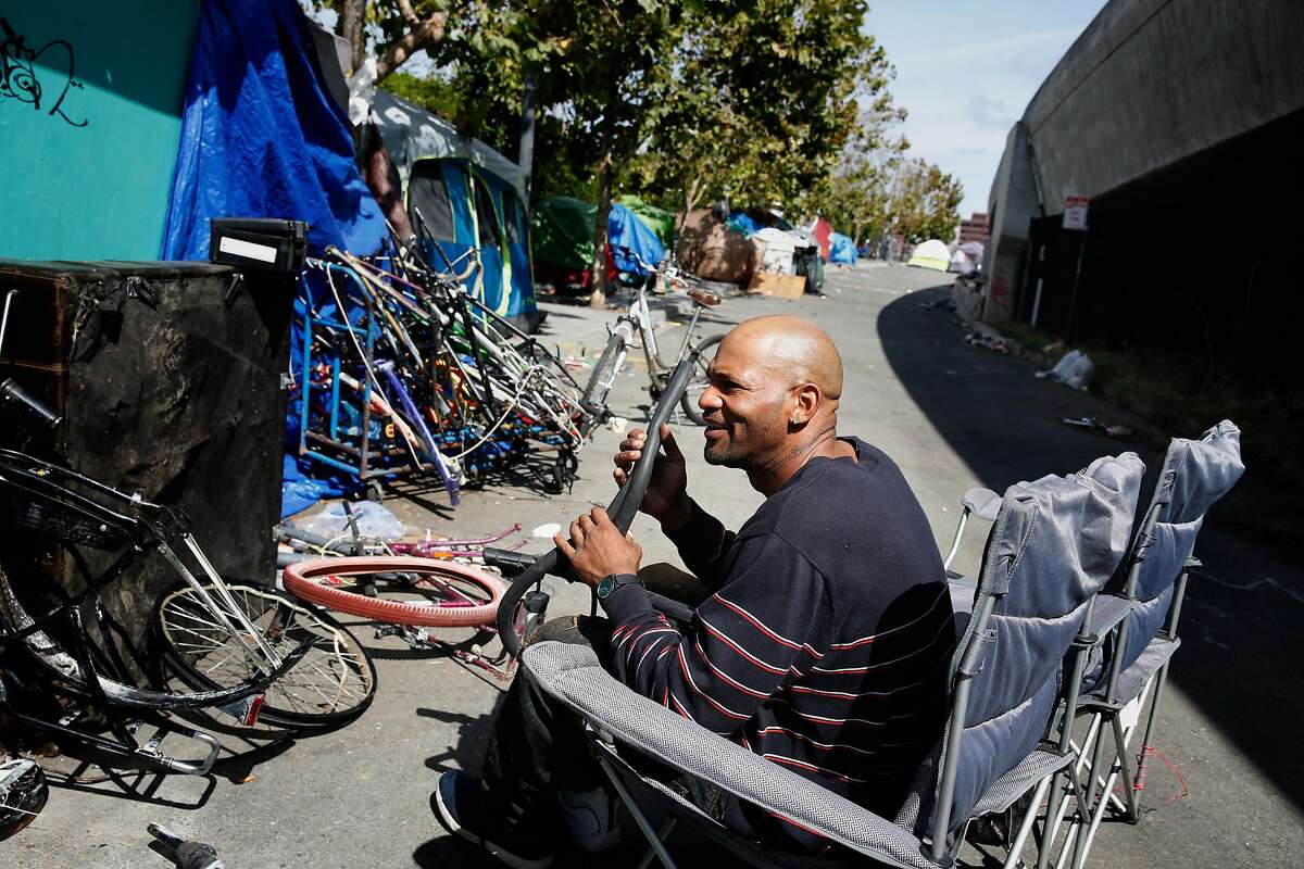 T.J. Brown fixes a bicycle tire along King Street at the homeless encampment where he lives on Friday, September 29, 2017 in San Francisco, Calif.