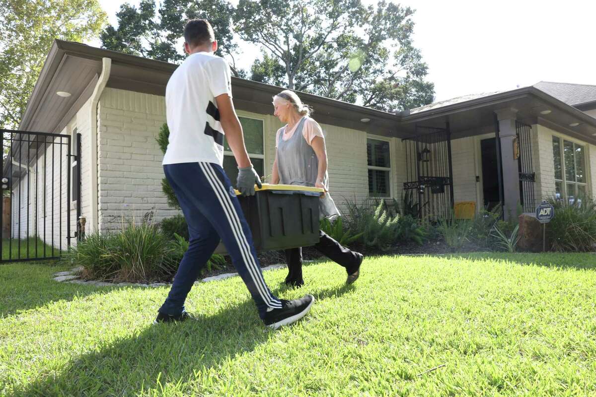 Volunteers carry dry items from a home that was damaged by Harvey on Sunday, Oct. 1, 2017, in Houston.