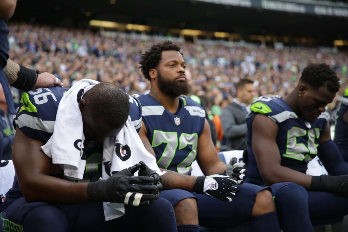 Seahawks players (l to r) Cliff Avril, Michael Bennett, and Frank Clark sit during the playing of the national anthem  before Seattle's game versus the Indianapolis Colts at CenturyLink Field on Sunday, Oct. 1, 2017.