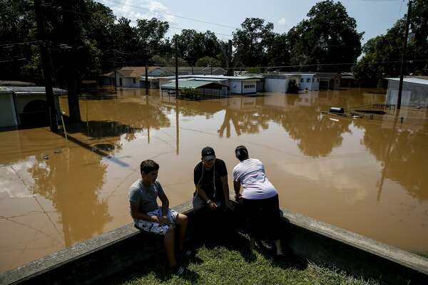 Rosalinda Gomez, right, peers down Damon Street as the flooded Brazos River runs through the neighborhood after Tropical Storm Harvey.