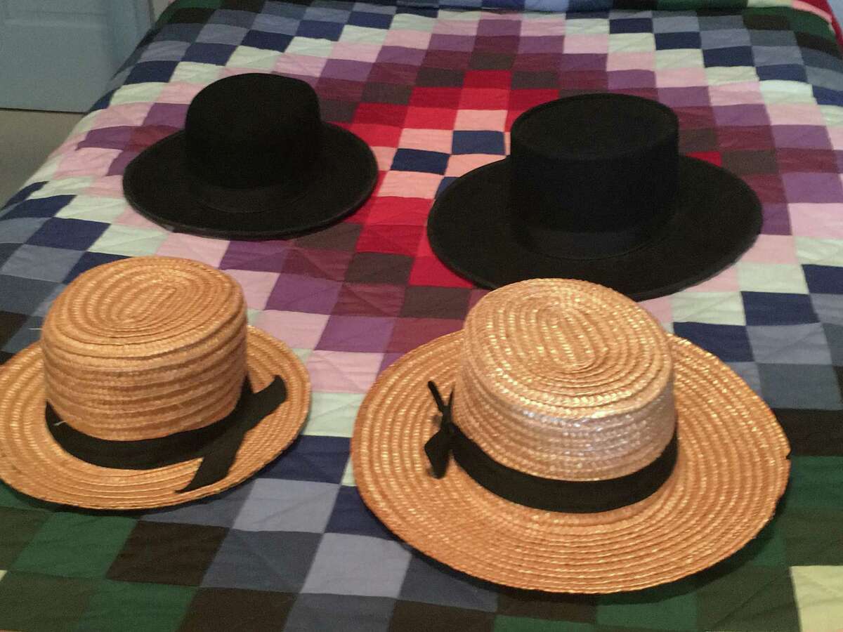 Amish men's everyday straw hats and dress hats sit on a typical Amish quilt.