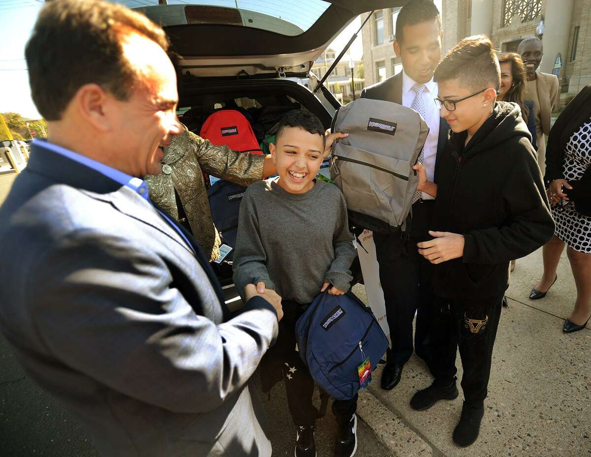 From left; Bridgeport Mayor Joe Ganim gives school backpacks to brothers Juan, 12, and Jan Casiano, 13, from Bayamon, Puerto Rico, outside City Hall in Bridgeport, Conn. on Thursday, October 5, 2017. The brothers, who are staying with Bridgeport relatives following the devastating hurricane in Puerto Rico, will begin attending Luis Munoz Marin School next week.