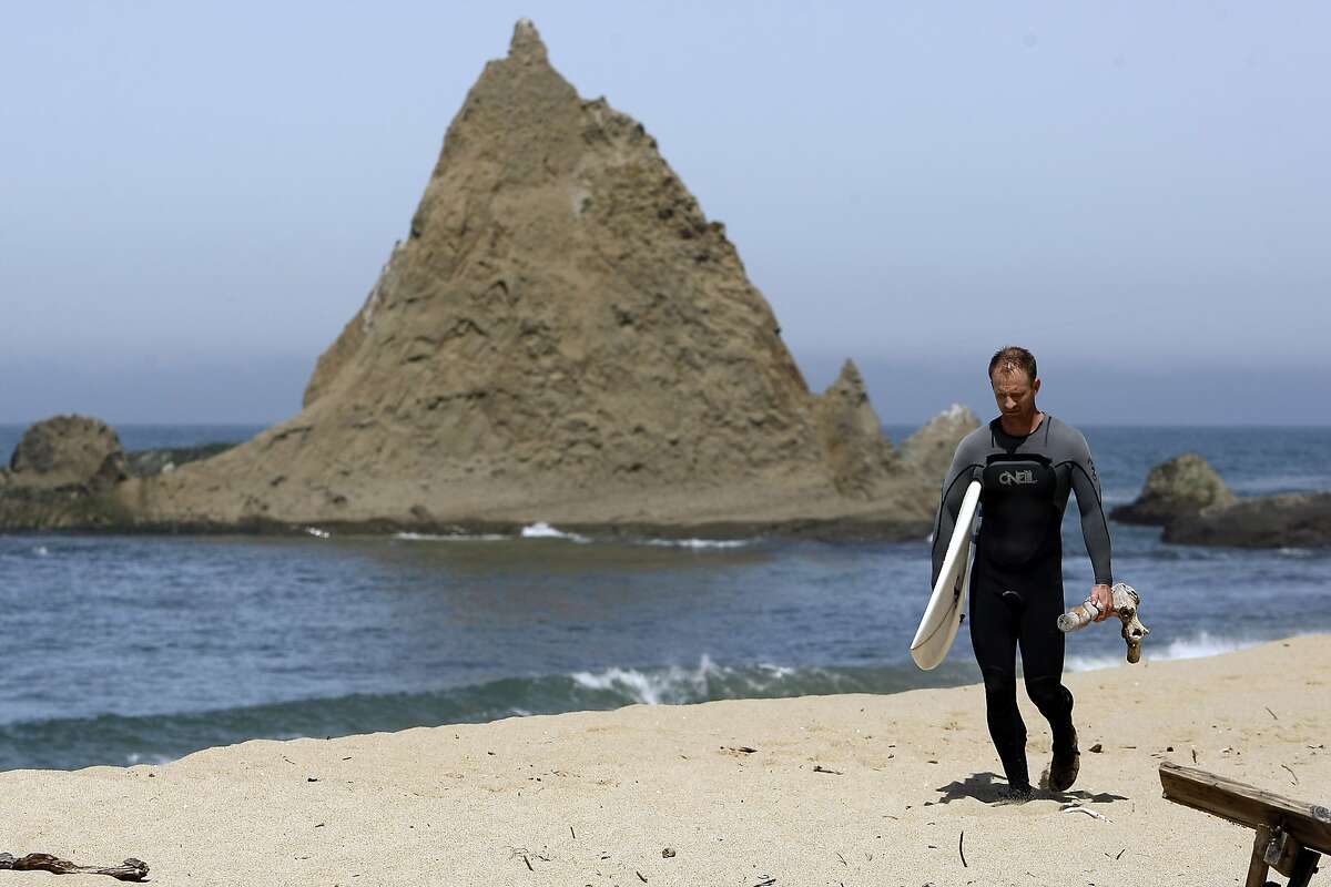 Surfer Danson Drummer of Mill Valley walks past the iconic Pelican Rock after surfing at Martin's Beach in Half Moon Bay, CA, Thursday May 15, 2014.