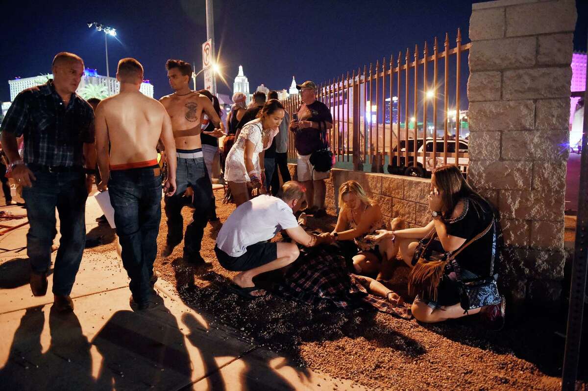 Concertgoers tend to the wounded outside the grounds of the Route 91 Harvest festival Sunday in Las Vegas. An apparent lone gunman killed 58 people and wounded hundreds more﻿.